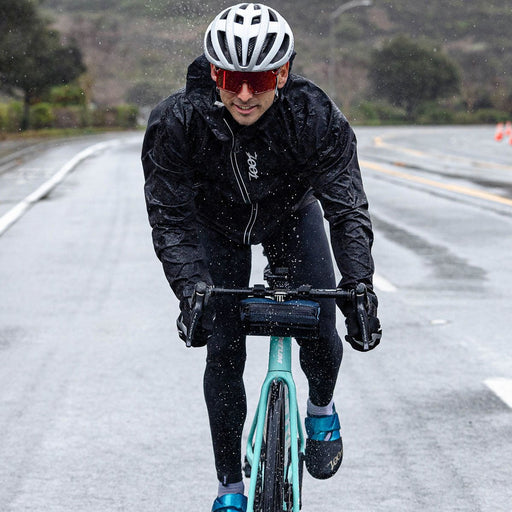 Male cyclist biking in the rain wearing Men's Elite FlashJacket - Black